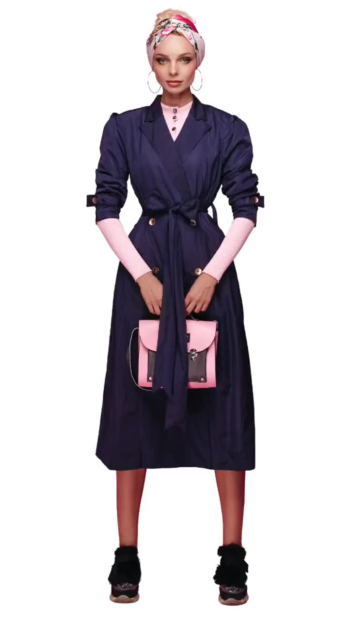 A model in a navy belted trench coat over a pink knit, holding a pink and charcoal satchel